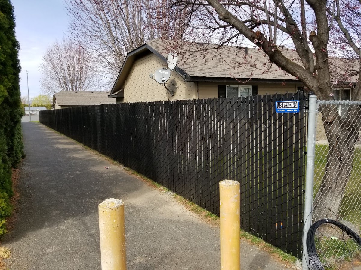 Black privacy-slat chain link fence with the L S Fencing sign installed in a Yakima neighborhood